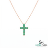 Cross-shaped pendant with emerald stones on a rose gold chain, branded 'SM Gems India'.